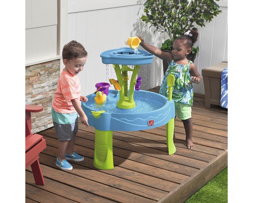 Deux enfants jouent à l''extérieur avec une table de jeu Step2 Waterfall Discovery Wall et des accessoires.