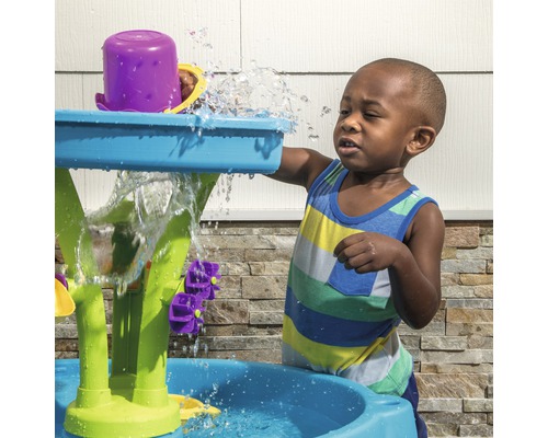 Un enfant joue avec une table de jeu d''eau à l''extérieur.