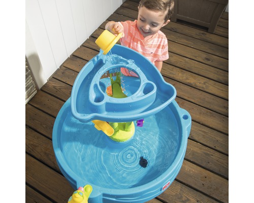 Garçon jouant avec une table de jeu d''eau bleue à l''extérieur