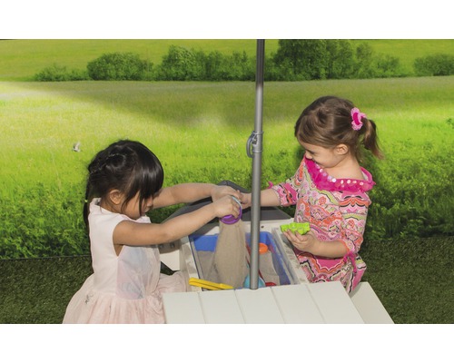Deux enfants jouent à une table à sable et à eau avec un parasol dans le jardin.