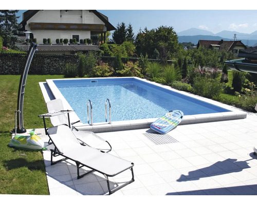 Piscine dans le jardin avec chaises longues et douche extérieure
