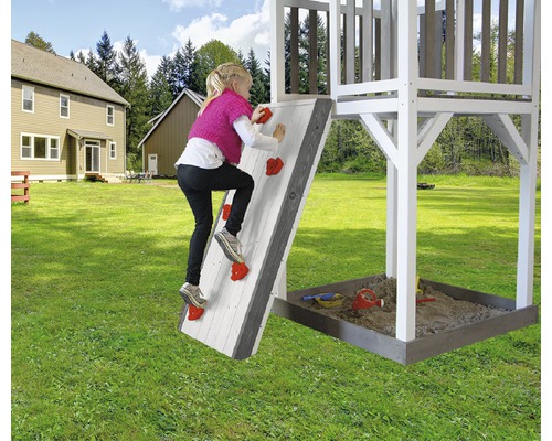 Un enfant escalade un mur d''escalade d''une aire de jeux dans le jardin.