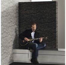 Scène avec un homme jouant de la guitare électrique devant un panneau mural à effet pierre