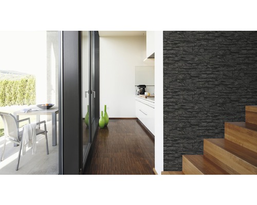 Heller Raum mit einer Wand in Steinoptik, Treppe und Blick auf eine Terrasse