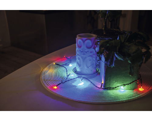 Décoration avec bougie, plantes d'intérieur et guirlande lumineuse sur une table