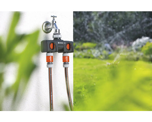 Distributeur d''eau Gardena sur un robinet avec deux tuyaux d''arrosage connectés.