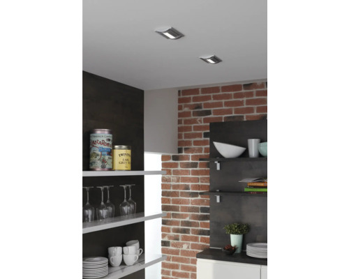 Scène de cuisine avec spots de plafond, mur en briques et étagères ouvertes avec de la vaisselle