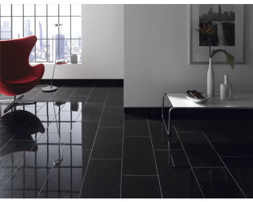 Pièce à vivre avec carrelage noir brillant, fauteuil, table et fenêtre