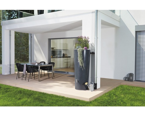 Extérieur avec un récupérateur d''eau de pluie à côté d''une descente pluviale, un arrosoir et une table à manger sur une terrasse