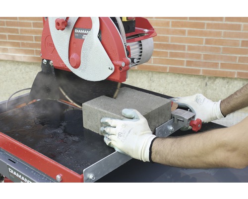 Une scie à pierre coupe un pavé.
