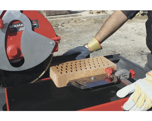 Une scie à pierre coupe une brique.