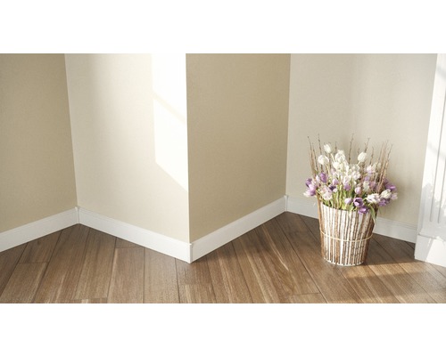 Coin de pièce avec plinthes, plancher en bois et composition florale dans un panier