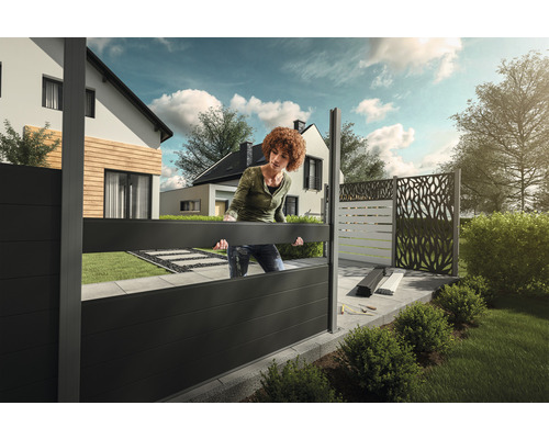 Une femme installe un écran d''intimité dans le jardin.