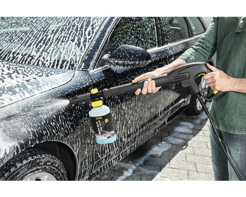 Eine Person reinigt ein Auto mit einem Kärcher Hochdruckreiniger und Reinigungsmittel.