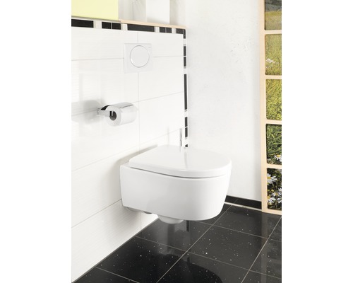 Wandhängendes WC mit Betätigungsplatte und Toilettenpapierhalter im Badezimmer.