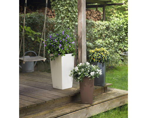 Drei hohe Pflanzgefäße mit bunten Blumen auf einer Holzterrasse