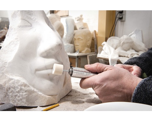 Gros plan d''une personne sculptant une sculpture en pierre avec un outil rotatif