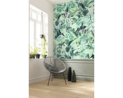 Dekoriertes Zimmer mit Dschungeltapete, rundem Stuhl und Zimmerpflanzen