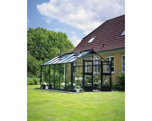 Serre JULIANA Premium 13 m² verre de sécurité 3 mm 296 x 439 cm anthracite/noir Serre sur pelouse à côté d''une maison avec un toit en tuiles.