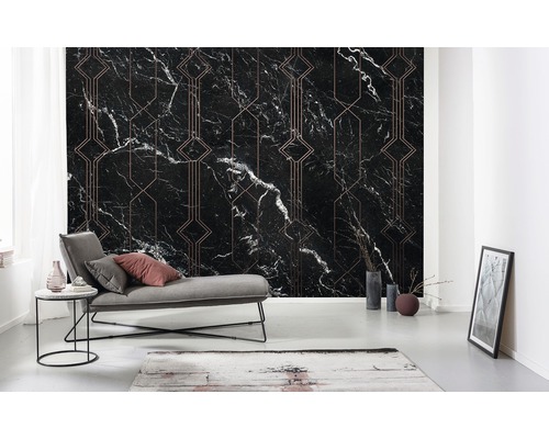 Salon avec un papier peint en marbre noir à motifs géométriques, une chaise longue grise et des éléments décoratifs.