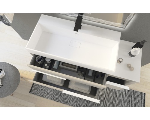 Badezimmer mit Waschbecken, Armatur, Spiegel und offenen Schubladen mit Handtüchern