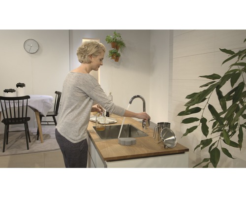 Cuisine claire avec femme à l''évier, robinet, évier et ustensiles de cuisine.