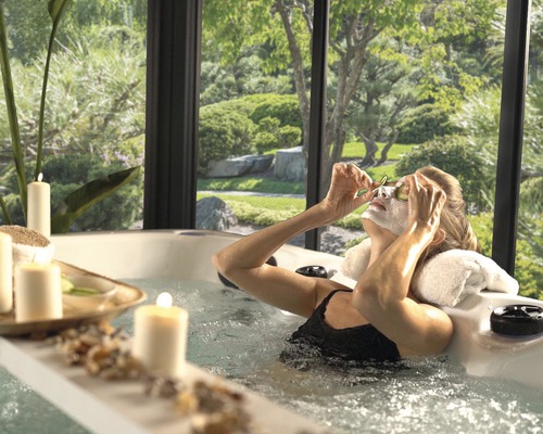 Femme se détend dans un bain à remous avec vue sur un jardin