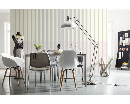 Salon avec table à manger, chaises, lampadaire et papier peint rayé pour une ambiance claire et organisée.