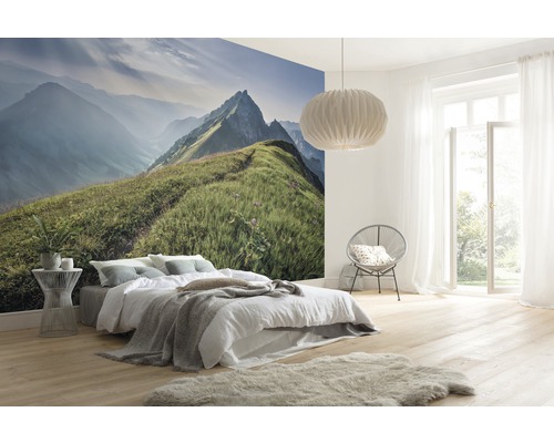 Chambre lumineuse avec papier peint photo paysage de montagne, lit, fauteuil, lampe et plancher en bois clair