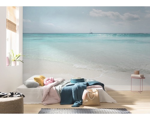 Salon avec papier peint photo représentant un paysage marin avec une plage et un voilier.