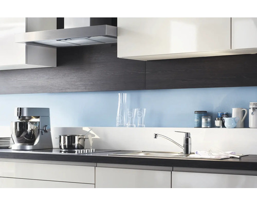 Scène de cuisine avec hotte aspirante, robot de cuisine, évier et plaque de cuisson dans un design de cuisine moderne.