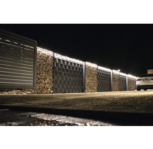 Gabionenwand mit Holzbefüllung und angrenzendem Zaun bei Nacht