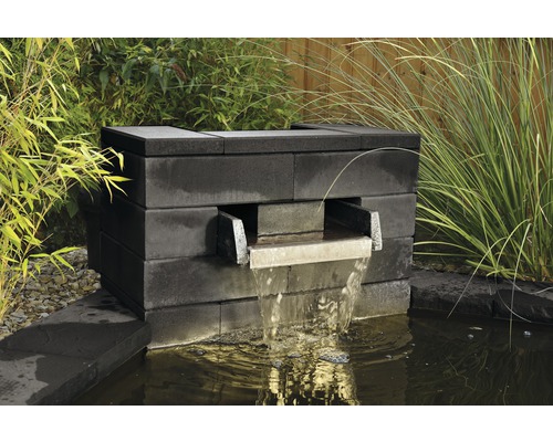 Fontaine de jardin en blocs de pierre avec écoulement d''eau dans un bassin de jardin