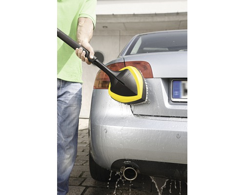 Une personne nettoie une voiture avec une brosse de lavage rotative de Kärcher.