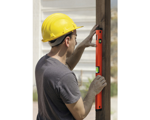 Homme avec casque de protection et niveau à bulle sur un poteau en bois