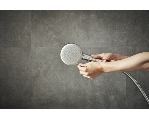 Douchette avec flexible de douche devant un mur carrelé