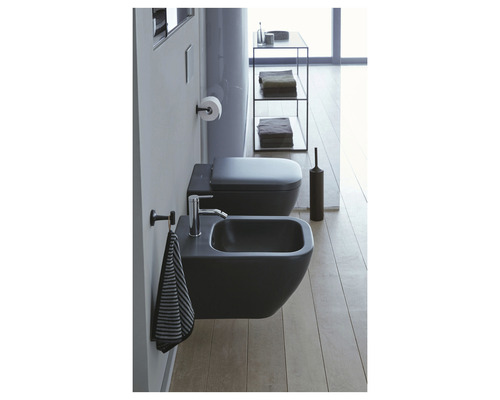 Badezimmer mit wandhängendem WC und Bidet sowie Handtuchhalter, Toilettenpapierhalter und Regal