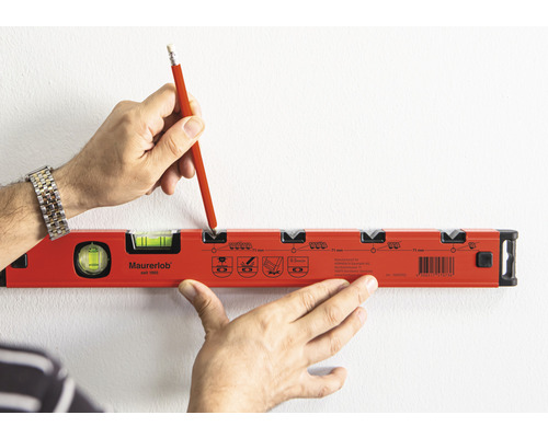 Eine Person markiert mit einem Bleistift eine Stelle auf einer Wand mit einer Wasserwaage.