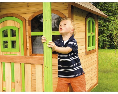 Garçon jouant devant une cabane en bois avec fenêtres