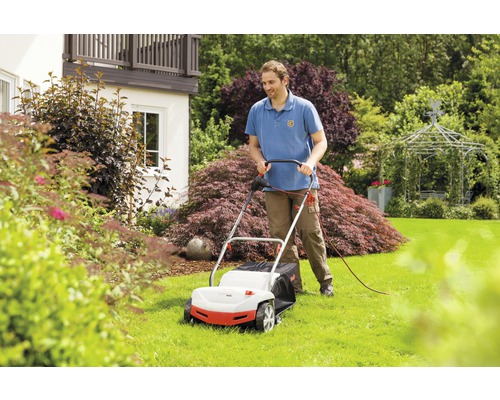 Un homme utilise une tondeuse à gazon dans le jardin.