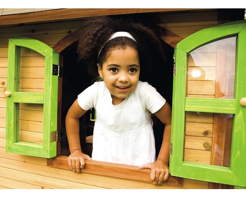 Un enfant regarde par la fenêtre d''une cabane en bois.