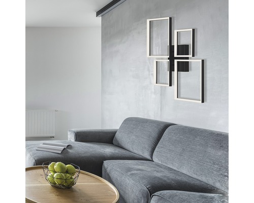 Salon avec canapé gris, table en bois avec coupe de fruits et applique murale aux formes rectangulaires