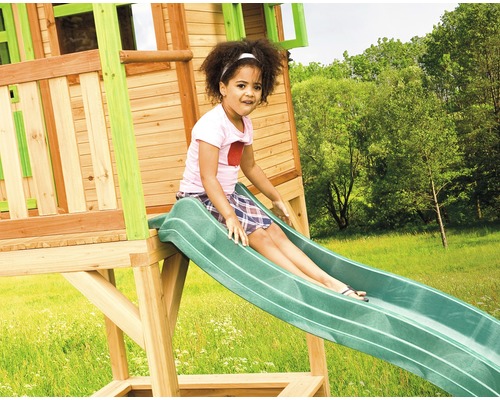 Fille glissant sur un toboggan de tour de jeux dans le jardin