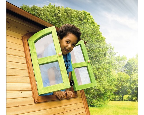 Garçon regardant par la fenêtre d''une cabane de jeu en bois