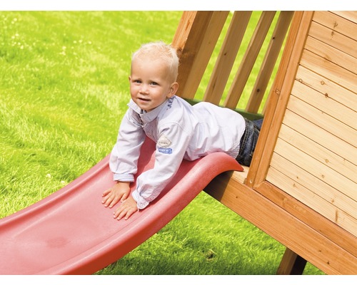 Enfant glissant sur un toboggan d''une cabane de jeu dans le jardin