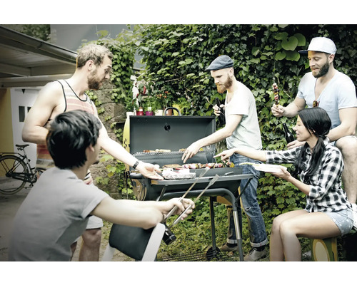 Un groupe d''amis fait des grillades dans le jardin avec un barbecue au charbon de bois et profite du temps passé ensemble.