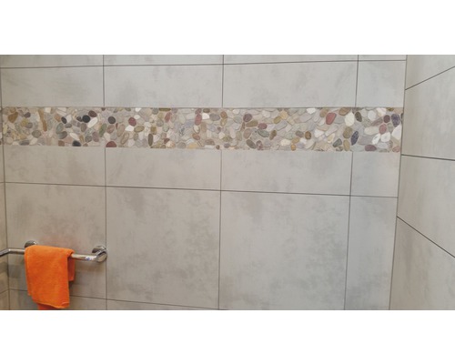 Carrelage mural avec bordure de galets dans une salle de bains.