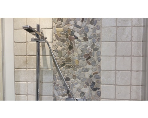 Gros plan d''une pomme de douche sur fond de galets et de carrelage