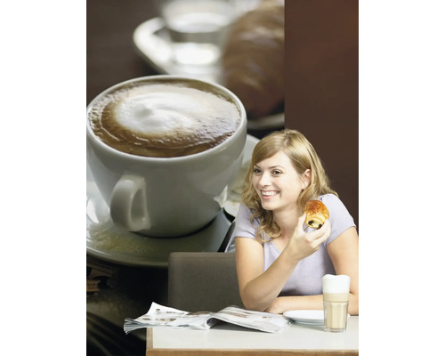 Une femme est assise à une table avec un café, un pain au chocolat et un magazine.