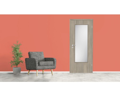 Porte intérieure en bois avec insert en verre, fauteuil et plante en pot devant un mur